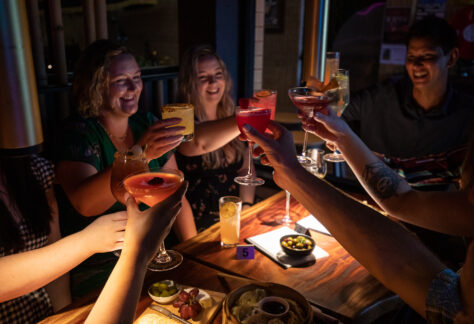 Women smiling while holding up their drinks for a toast in Dom's Bar and Lounge