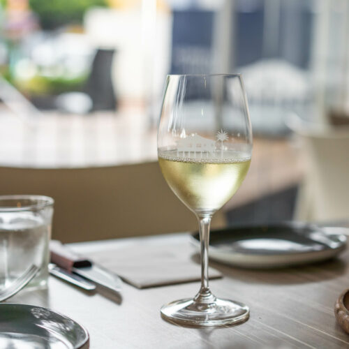 char restaurant table set with a glass of white wine ready for guest