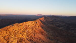 the sunset making a mountain range glow orange, with the sky and the rest of the sunset in the horizon/background