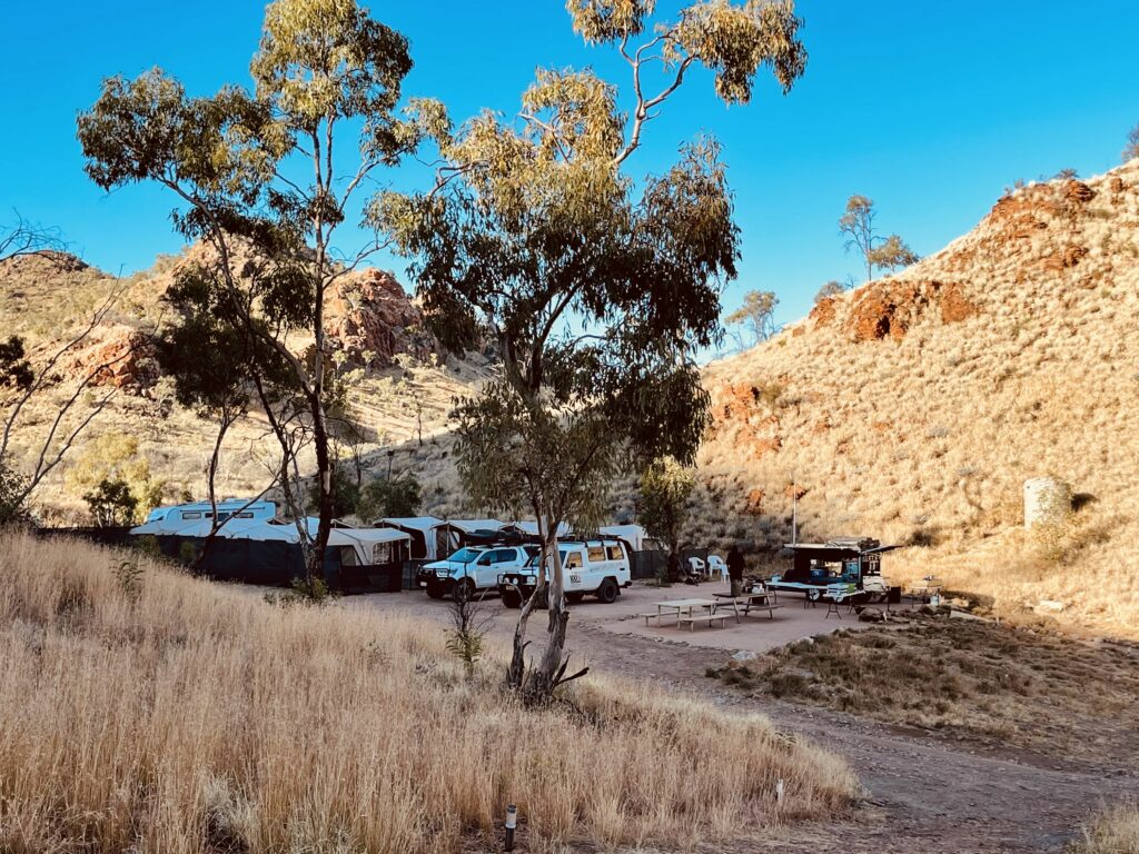 Picture of 4WD, trees, picnic tables in a camping spot in Larapinta Trail