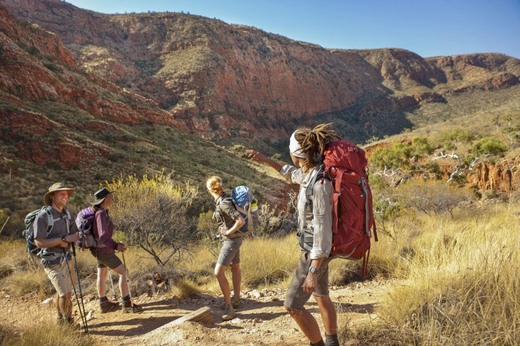 hikers with backpacks hiking with mountains in backdrop in Northern Territory