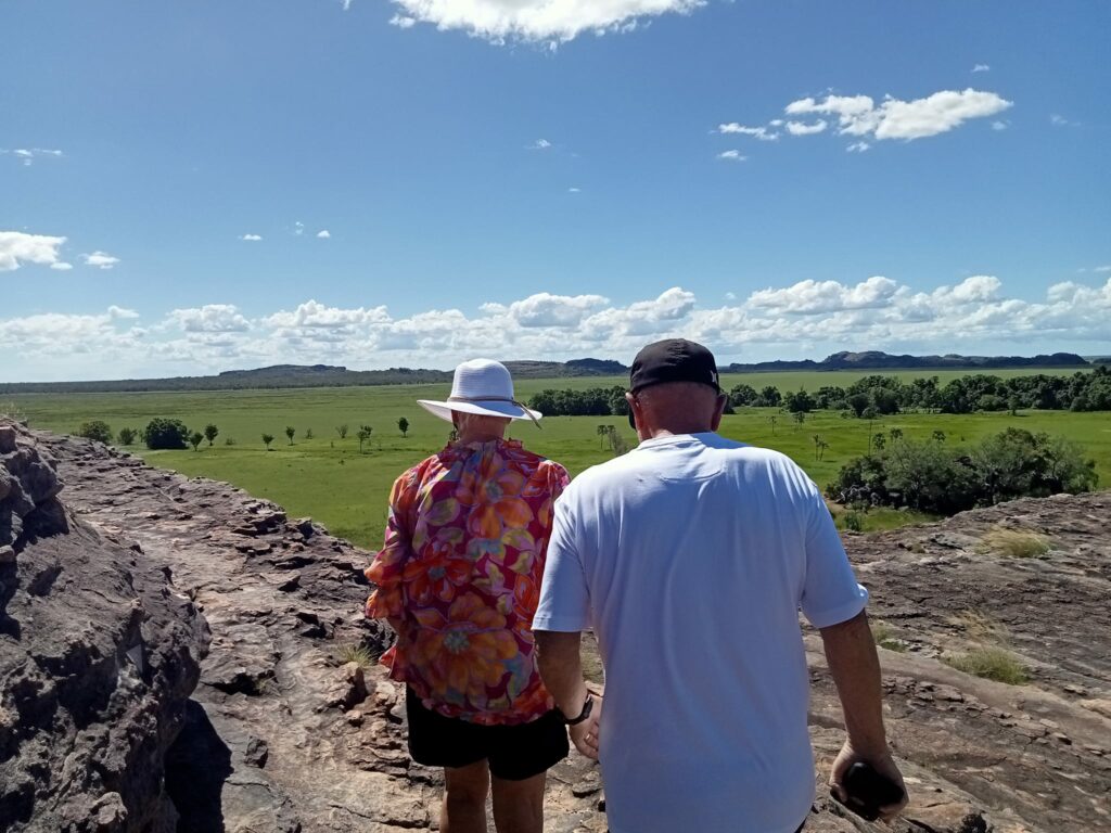 man and woman walking with green Northern Territory landscapes in backdrop with blue skies