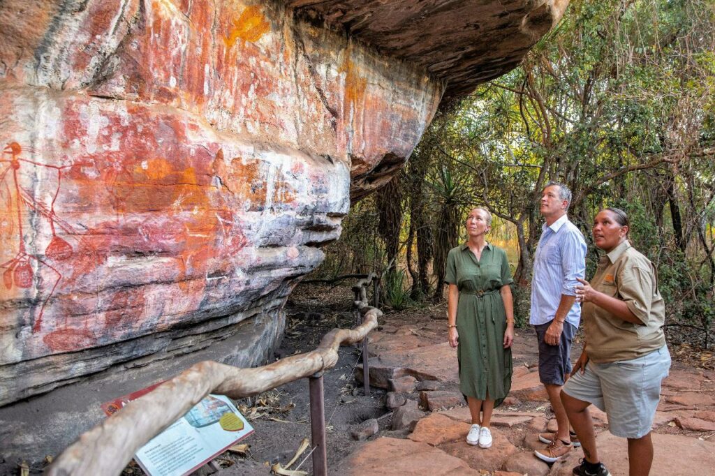 man and woman looking at ancient rock art with guide
