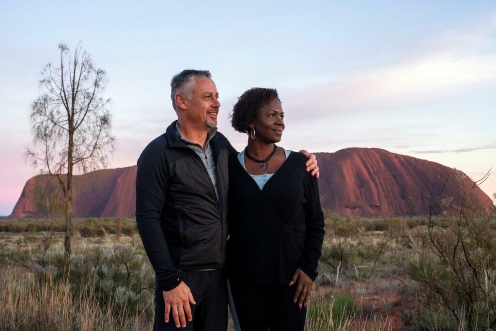 two people posing for a picture in front of Uluru