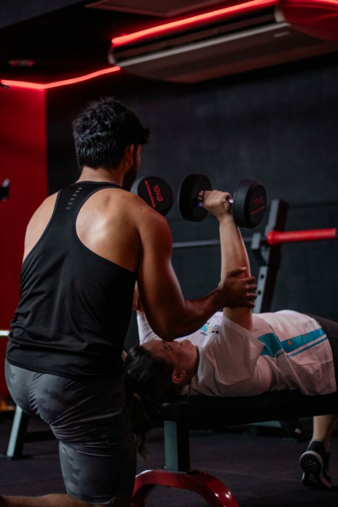 one more fitness club darwin personal trainer helping a man lift weights